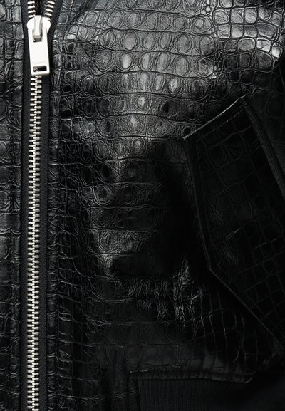 Must nahkjope krokodillinaha tekstuuriga, hõbedase luku ja klapiga tasku detailiga.