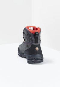 Botte de randonnée noire avec une fermeture texturée, un col en mailles rouges contrastantes et un logo au niveau du talon. Matériau durable avec un design robuste.