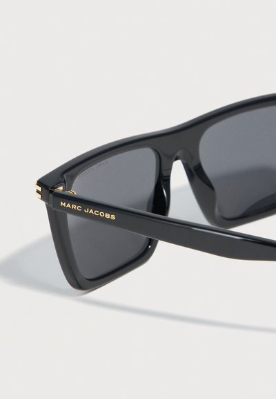 Μαύρα ορθογώνια γυαλιά ηλίου με σκουρόχρωμους φακούς, χρυσά μεντεσέδες και λογότυπο «MARC JACOBS» σε χρυσό στη πλαϊνή βραχίονα.