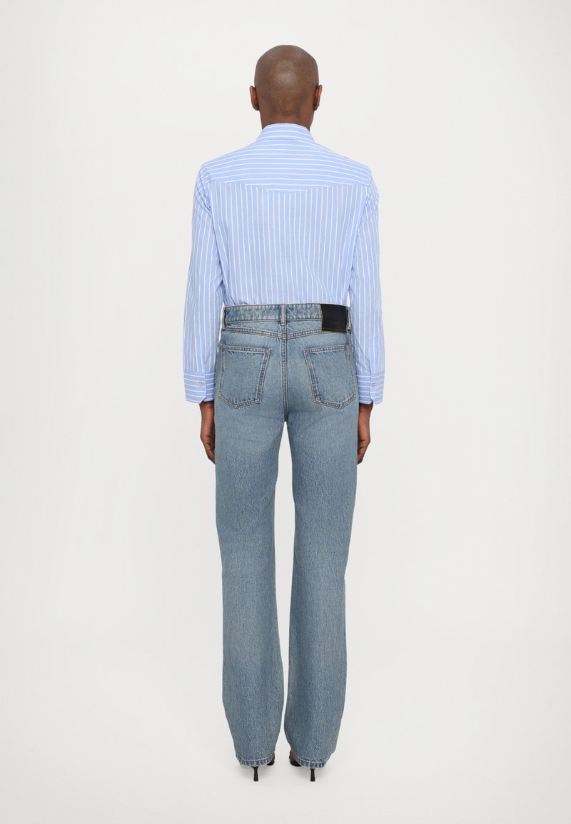 Light blue striped long-sleeve shirt paired with high-waisted, loose-fit light denim jeans. Notable details include a black leather label on the waistband.