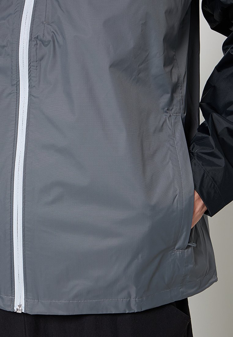Chaqueta impermeable gris con una superficie texturizada, cierre frontal con cremallera y bolsillo laterales, con mangas negras para contraste.