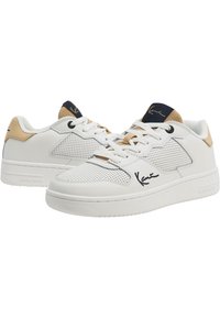 Zapatillas blancas de cuero con paneles perforados, acento en azul marino en la lengüeta, taberna beige en el talón y detalle negro de firma en el costado. Suela de goma plana.
