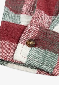 Rood, groen en wit geruit stof met een gestructureerde weving. Bevat een knoopsluiting op een omgerolde rand.