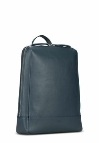 Sac à dos en cuir bleu foncé, forme rectangulaire, équipé d'une poignée supérieure, d'une fermeture à double glissière et d'une surface texturée.