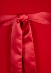 Rött tyg med en slät textur har en röd satinrosett knuten i en knut, som framhäver dess övergripande design.