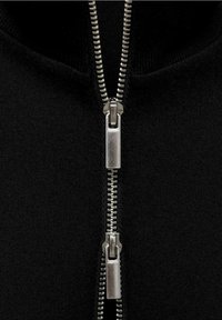 Sort zip-up hættetrøje med en metallisk lynlås med glatte tænder, kontrasterende tekstur mod stoffet og et hævet kravedesign.