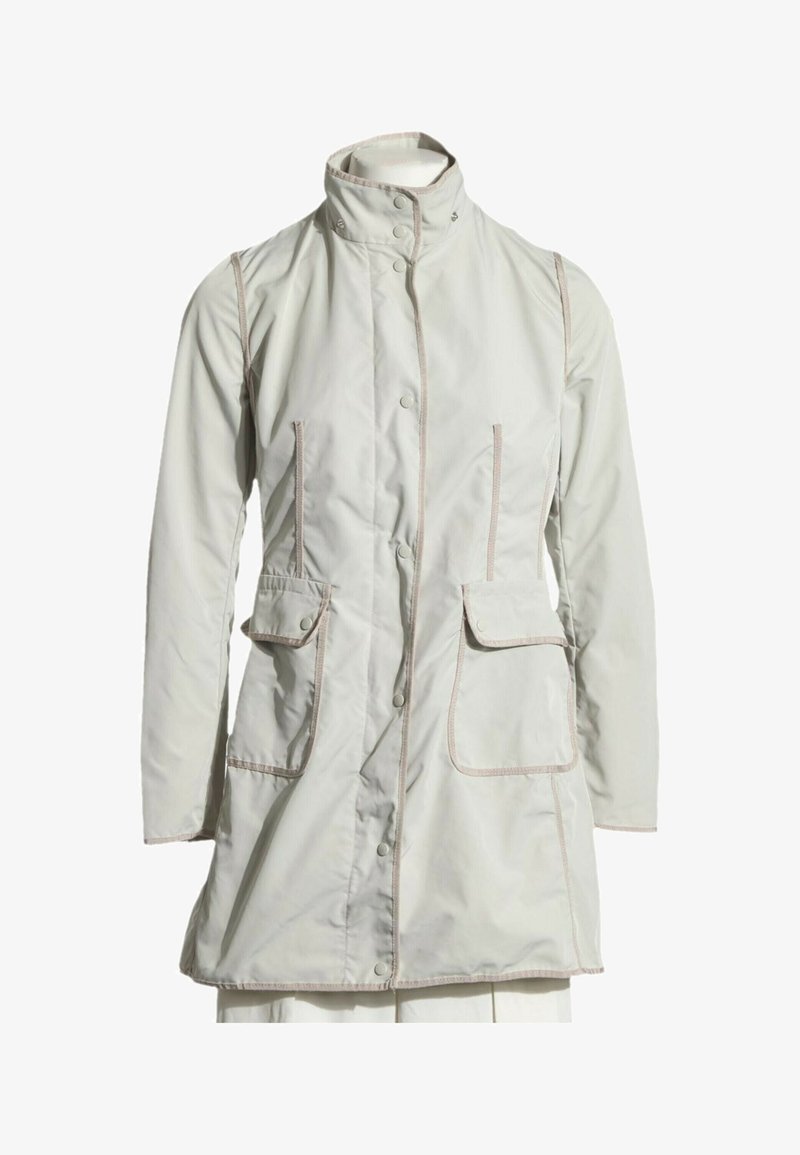Manteau beige clair à manches longues avec col montant, boutons-pression à l’avant, deux poches à rabat et surpiqûres contrastées le long des bords.