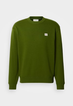 Roheline puuvillane sviiter ümarate kaelustega, ribatud mansettide ja äärtega. Ülaservas vasakus nurgas on väike tikandiga logo.