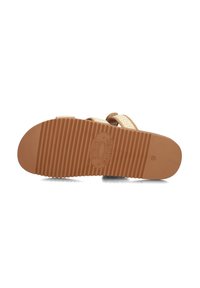 Tan rubberen sandaalzool met een gestructureerd oppervlak, gemarkeerd logo en ondiepe groeven voor grip. Platte, brede vorm met een ronde neus.