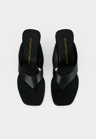 Paire de sandales en cuir noir à enfiler avec bouts carrés et larges brides, comportant l'inscription dorée « Stuart Weitzman » sur les semelles intérieures.