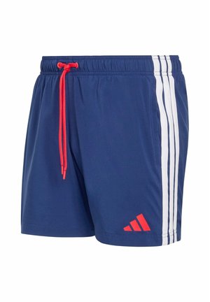 Pantalones cortos deportivos azul marino con rayas blancas en los costados, cordón rojo en la cintura y logo rojo de Adidas cerca del dobladillo en la pierna izquierda.