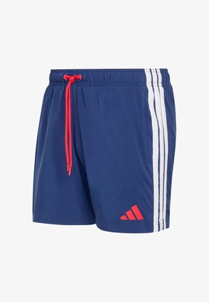 Pantalones cortos deportivos azul marino con rayas blancas en los costados, cordón rojo en la cintura y logo rojo de Adidas cerca del dobladillo en la pierna izquierda.
