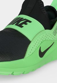 Μαύρο και νέον πράσινο sneaker Nike χωρίς κορδόνια με ελαστική ταινία στην κορυφή και λογότυπο Nike swoosh στο πλάι.