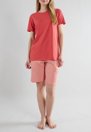 Koraalkleurig T-shirt met korte mouwen, gecombineerd met knielange shorts in een rood-witte ruitpatroon. Zacht katoen, casual pasvorm.