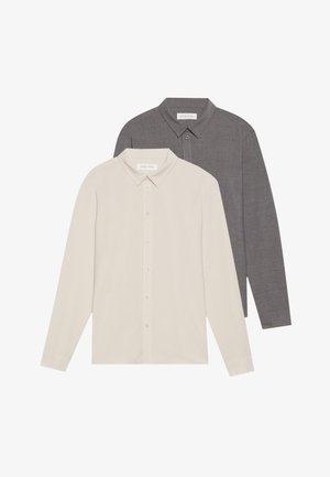 Two long-sleeve shirts: one beige, the other dark gray. Both feature collared necklines and front button closures with a smooth texture.