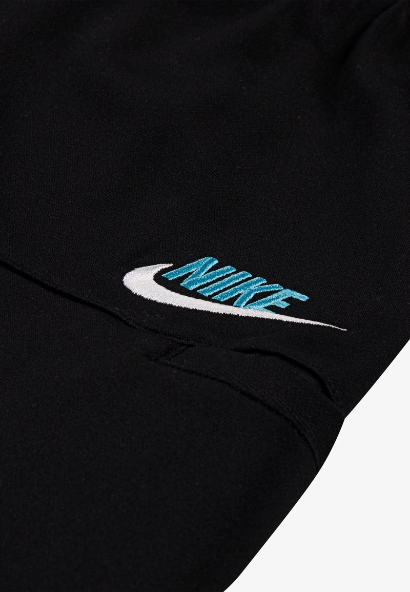 Bermudas deportivas negras hechas de tejido suave, con el logo de Swoosh de Nike en blanco y letras turquesa. Cintura elástica para mayor comodidad.