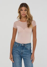 Body rosa chiaro a maniche corte con dettagli in rete sulle spalle e sul collo, abbinato a jeans in denim blu a vita alta.