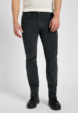 Ciemnoszare spodnie z groszkowanej tkaniny w slim fit, z delikatną pionową teksturą i standardowym pięciopocketowym krojem, noszone z czarnymi butami.