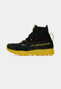 Melns augstais sporta apavu modelis ar dzeltenu zoli un akcentiem. Tam ir teksturēts augšdaļa, šņorējuma sistēma un pastiprināta pirkstu daļa atbalstam.
