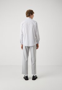 White and gray striped shirt with long sleeves, paired with light gray trousers and black shoes. Smooth texture, standard collar, tailored fit.