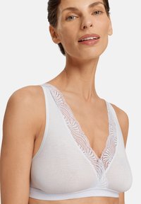 Bílý braletka s hlubokým V výstřihem a krajkovým lemem na ramínkách. Vyrobeno z měkké, hladké látky s pohodlným střihem.