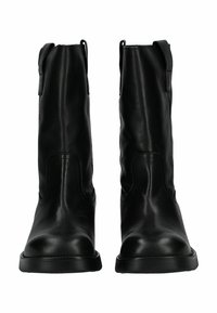 Botas de tobillo de cuero negro con tiradores laterales, textura suave, punta redondeada y detalle de costura mínima. Suela de goma plana.