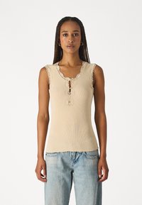 Beige ribaga tank top pitsmeki äärisega, võtmeaugu detailiga dekoltees ja mõnusalt istuv disain. Kombineeritud helesiniste laiadest teksadest.