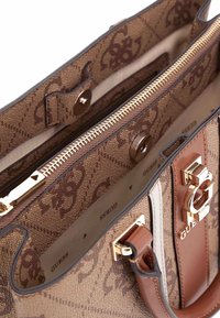 Bolso marrón con estampado y herrajes dorados, un compartimento con cremallera y una correa de cuero. Presenta acentos de logo y un interior textil.