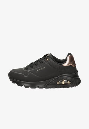 Chaussure de sport noire avec des panneaux perforés, texture lisse et accents en bronze. Dispose d'une semelle rembourrée avec coussin d'air pour le confort.