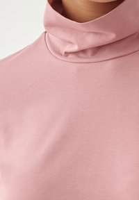 Růžový rolák vyrobený z hladkého, elastického materiálu. Vybavený stočeným límcem a slim fit střihem, zdůrazňující jednoduchý, minimalistický design.