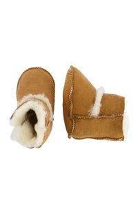 Tanschoenen van zacht suede met een pluizige schapenvachtvoering. Beschikt over gestikte accenten en een ronde vorm. Gezellig, gesloten ontwerp.