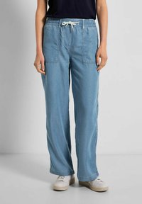 Pantalones de mezclilla sueltos en azul claro con cinturilla elástica y cordón blanco. Cuenta con dos bolsillos frontales tipo parche.