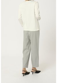 Maglietta bianca a maniche lunghe, pantaloni grigi a vestibilità ampia e scarpe nere con tacco kitten. Design semplice con tessuto morbido e cuciture sottili.