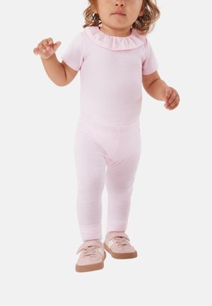 Kleinkind trägt einen Hellrosa-Strampler mit Rüschenkragen, passende Leggings und pinke Sneaker mit Klettverschluss, steht mit leicht erhobenen Armen.