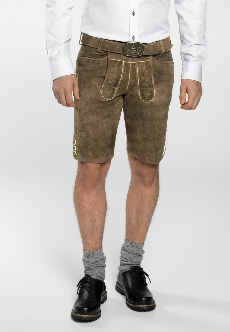 Pantalones cortos de lederhosen de ante marrón con costuras decorativas, botones laterales y un cinturón a juego con una hebilla grabada. Llevados con calcetas grises hasta la rodilla.