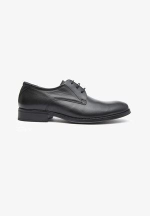 Zapato de cuero negro con cordones, de textura suave, punta redondeada y tacón bajo. Presenta costuras a lo largo de los bordes y un diseño minimalista.