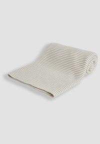 Woven cotton blanket in cream color, featuring a textured ribbed pattern and rolled edge. Compact rectangular shape, suitable for various uses.