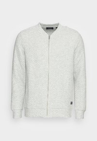 Sweat-shirt gris clair à fermeture éclair avec un tissu texturé, des poignets en côtes et un col rond. Présente une petite étiquette logo sur le côté.