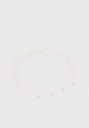 Collier délicat avec de petites perles translucides et des breloques roses en forme de goutte régulièrement espacées sur un fond clair.