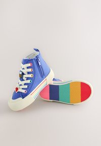 Sneakers alte in tela blu con zip, occhielli colorati per i lacci e due applicazioni. La suola presenta un motivo a strisce multicolore.