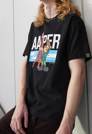 T-shirt nera in cotone con una grafica di un gorilla in stile cartoon e la Torre Eiffel, con un testo bianco audace che recita "AAPER" sopra.