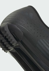 Zapato deportivo negro con parte superior texturizada, perforaciones para la transpirabilidad y suela resistente. Incluye líneas de diseño y collar acolchado.