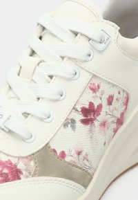 Baskets blanches avec panneau en textile à motif floral comprenant des fleurs roses. Cuir lisse, accents texturés et lacets blancs complètent le design.