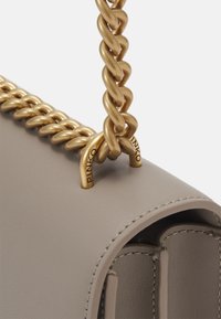 Borsa a tracolla rettangolare in pelle beige con finitura texture, dotata di una robusta catenina dorata e dettagli di branding in rilievo sulle cornici.