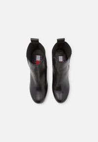 Paire de bottines en cuir lisse noir avec languettes de tirage et semelles intérieures de marque, vues de dessus sur fond blanc.