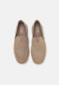 Beige ruskinds slip-on sko med elastiske sidepaneler, rundet tå og kontrasterende syninger. Gummisål med struktureret overflade.