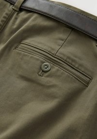 Olive green trousers with a buttoned back pocket, made of smooth fabric, featuring contrasting stitching and a sleek dark belt.