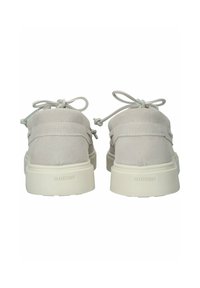 Zapatos de ante beige con punta redonda, cordones acentuados y suela de goma blanca, que presentan un logotipo sutil en el talón.