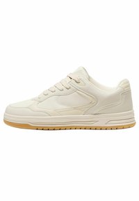 Beżowe buty sportowe o eleganckim, niskim kroju. Wykonane z gładkiego materiału syntetycznego, mają sznurowane zapięcie oraz podeszwę z gumy.
