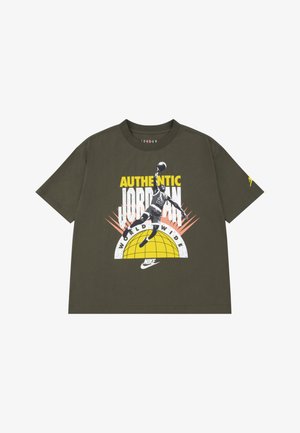 T-shirt en coton vert olive à manches courtes, avec un graphisme d'un joueur en plein saut. Le texte indique « AUTHENTIC JORDAN WORLDWIDE » et « NIKE ».